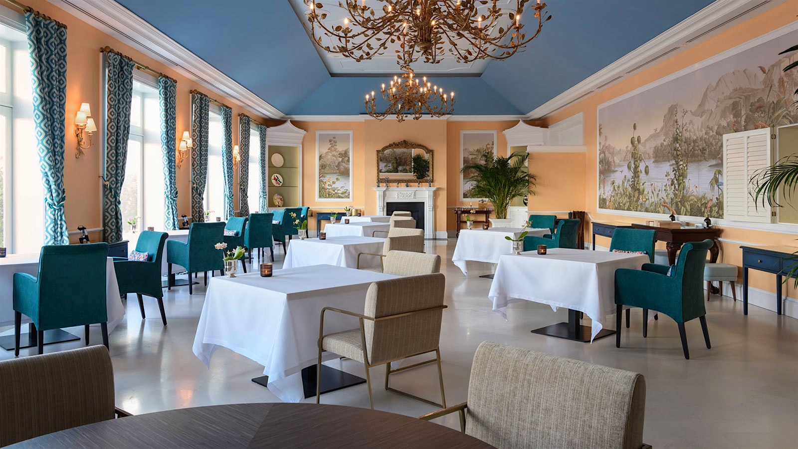 The dining room at the Yeatman, with chandeliers and a mural on the wall, along with mid-century style chairs